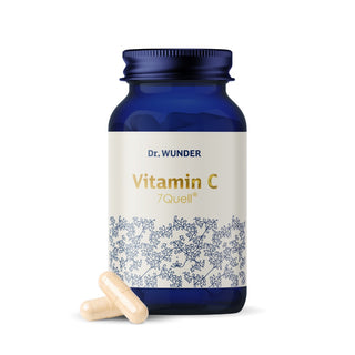 Vitamin C 7Quell von Dr. Wunder – dunkelblaue Glasflasche mit cremefarbenem Etikett und zwei beigen Kapseln davor
